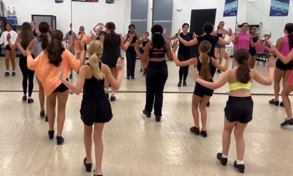 dance students learning a tap dance routine and practicing in front of a mirror